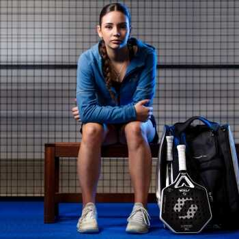 Tüdruk istumas pingil, tema kõrval maas spordikott ja reketid