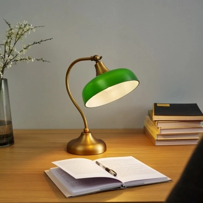 Roheline laualamp laual valgustamas lahtist raamatut